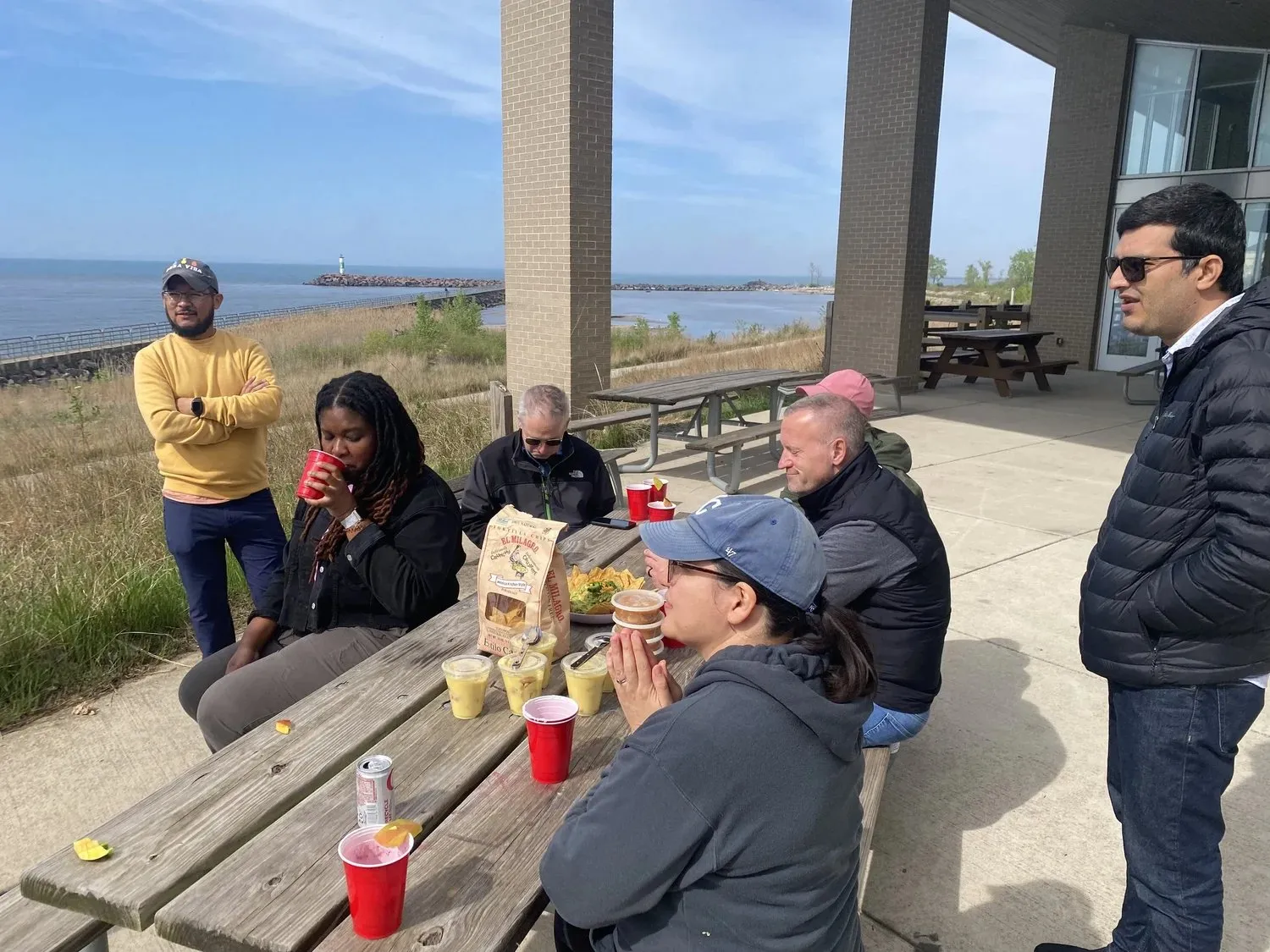 Colleagues talking around a picnic table by the lake during a team outing