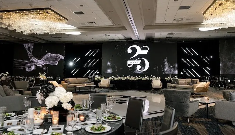 Ballroom with round tables and large screens set for a company anniversary dinner