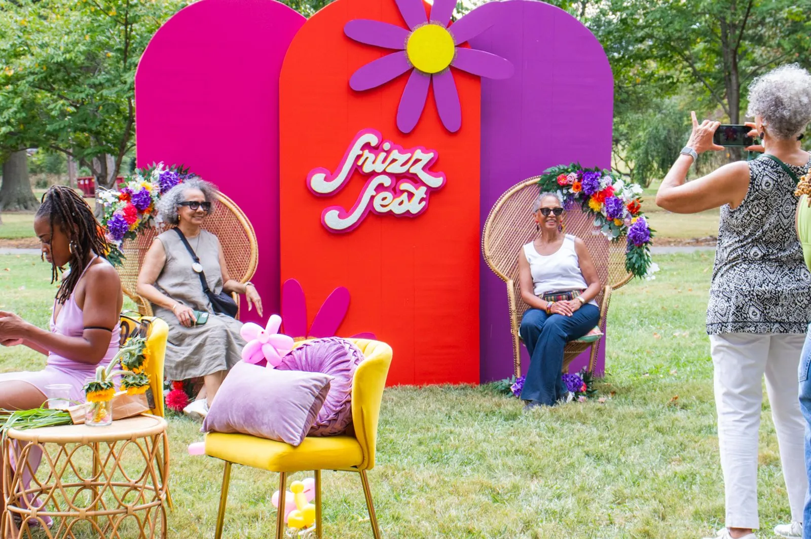 Guests at a colorful Frizz Fest photo backdrop on a lawn