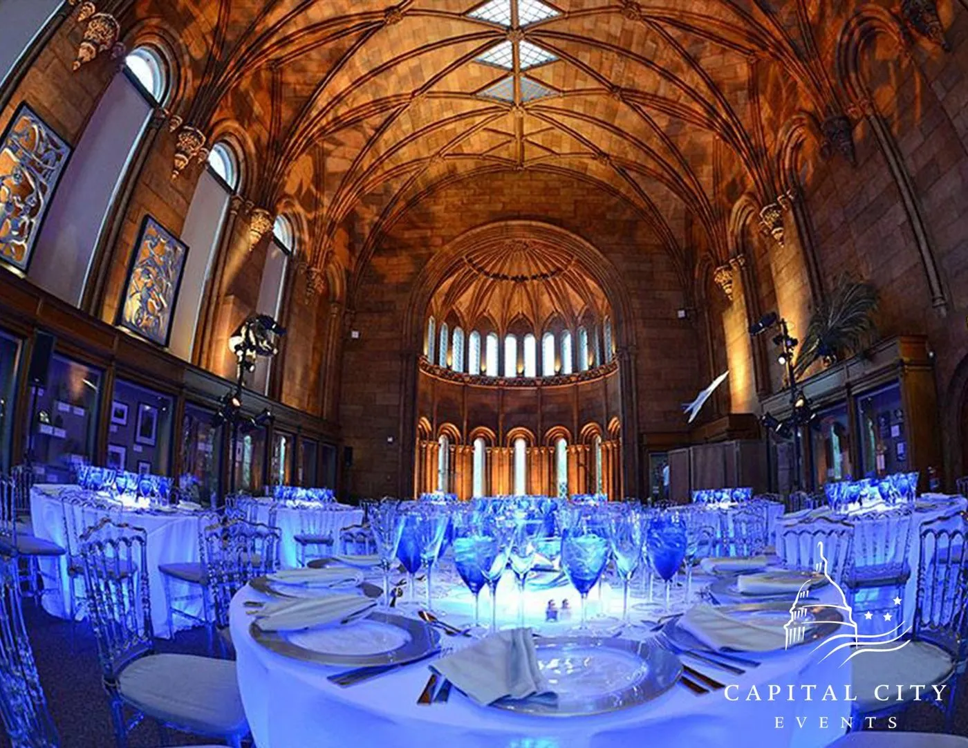 Dinner tables set under a vaulted historic library ceiling