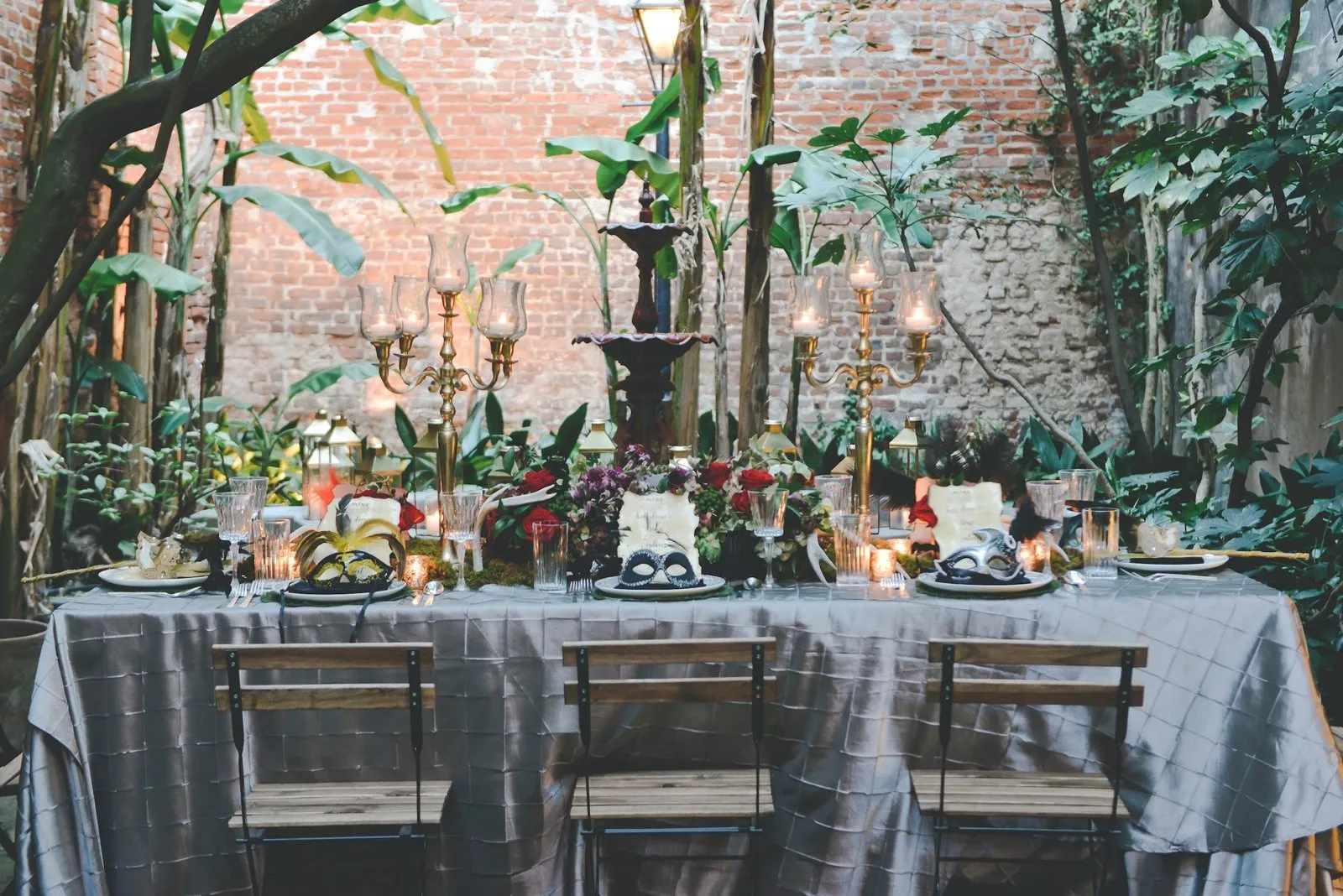Candlelit dinner table set in a leafy New Orleans courtyard