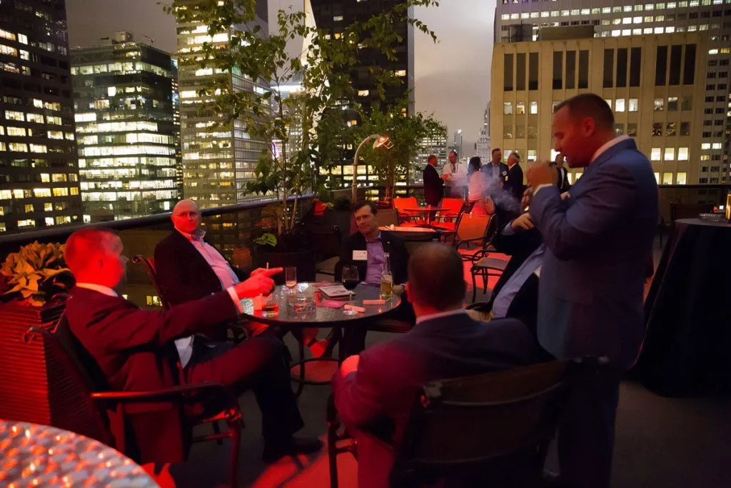 Guests networking on a city rooftop at dusk
