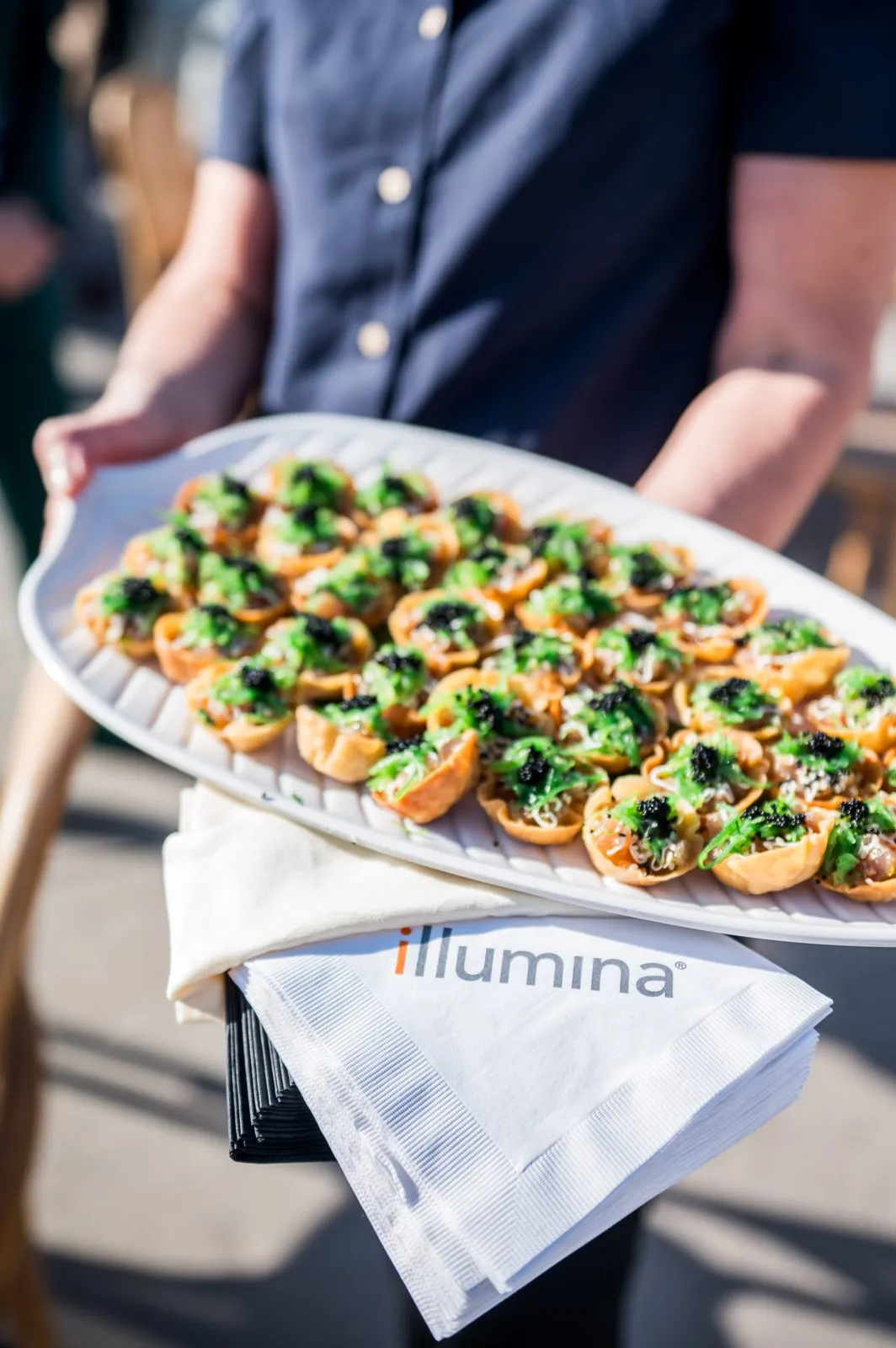 Server carrying a tray of appetizers with a branded napkin at a corporate event