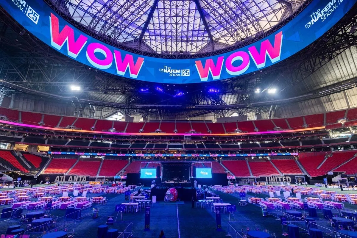 Stadium bowl set with long lounge tables and a large lit video ring for a group event