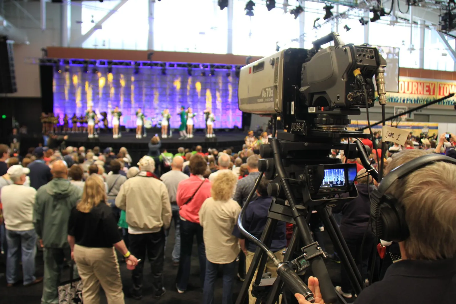 Stage with presenters lit in purple and a camera in the foreground
