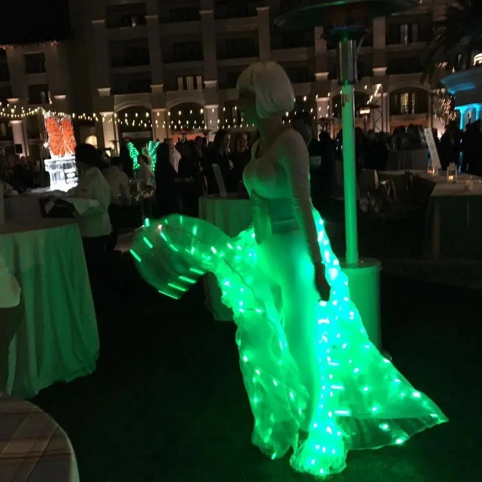 Performer in a light-up green gown at an evening outdoor reception