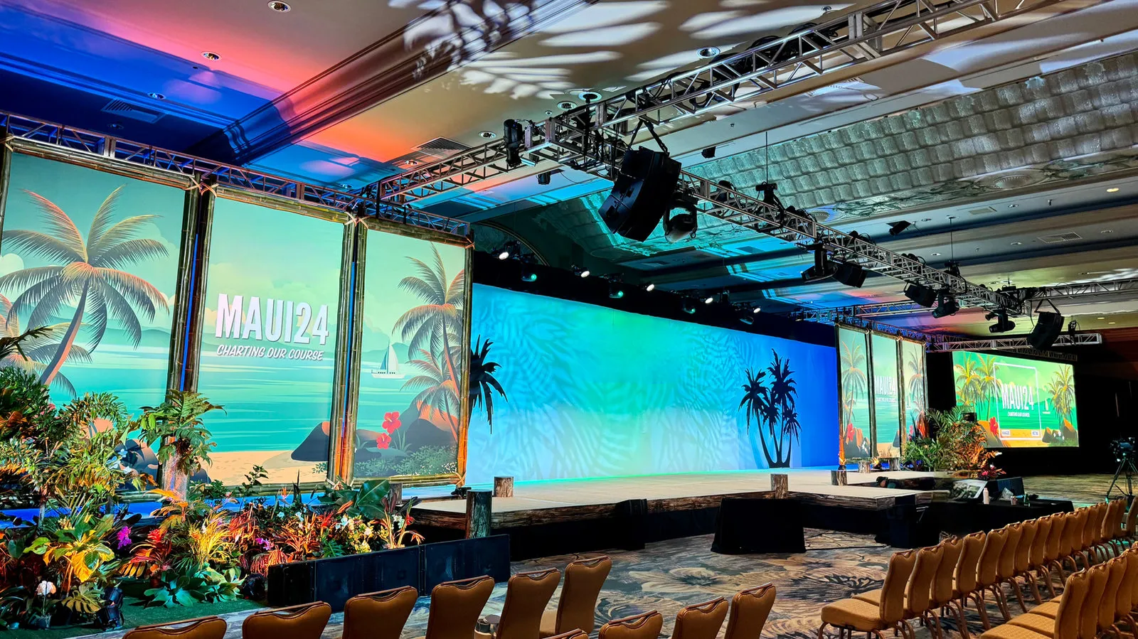 Ballroom general session with palm-tree LED screens and tropical floral arrangements, produced by AVS Audio Visual Services Hawaii