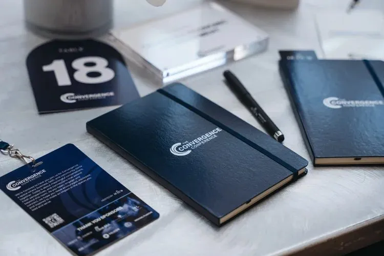 Branded notebooks, lanyards and printed materials laid out on a conference table