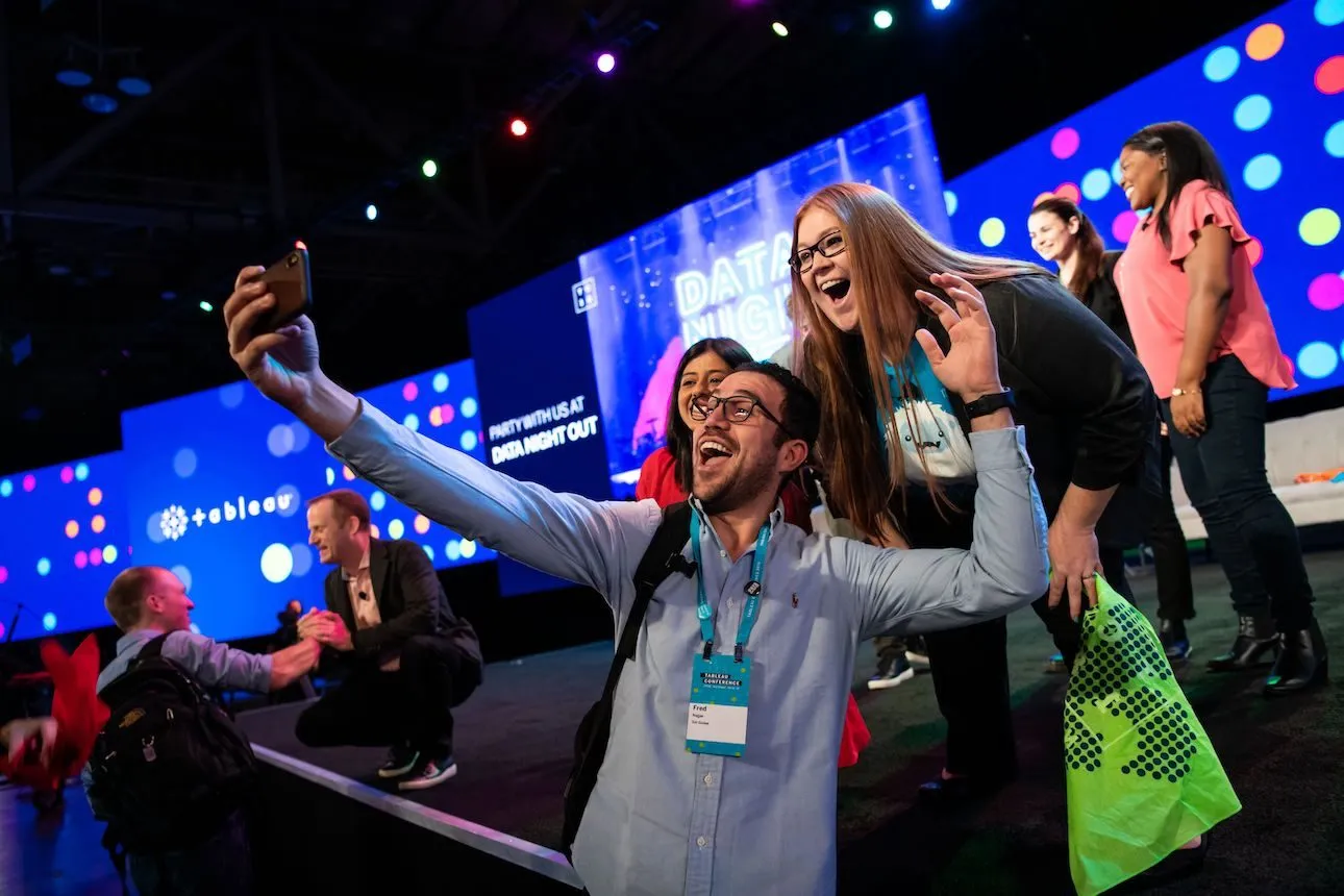 Attendees taking a selfie in front of a colorful conference stage