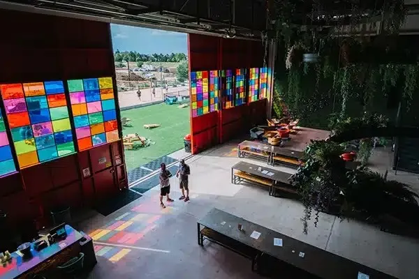 Event venue with colorful light panels and a lounge stage opening onto a lawn