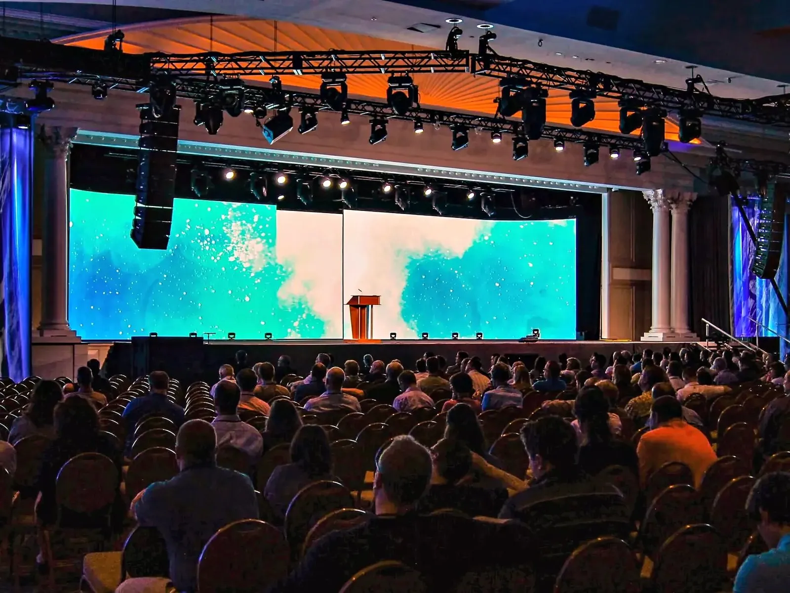 Conference general session with a large LED video wall, lectern and a full house