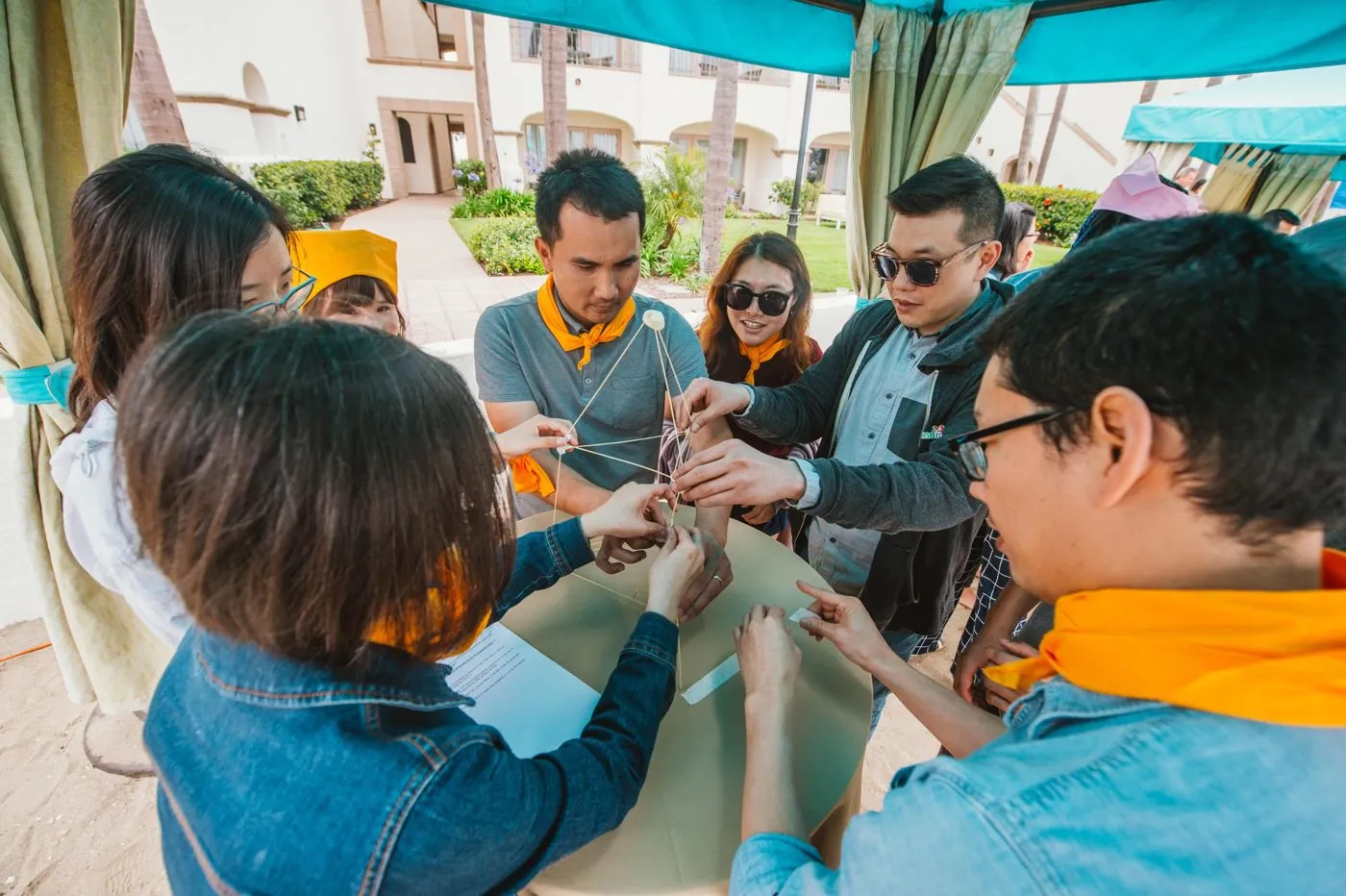 Team members working on a hands on challenge at a table under a cabana
