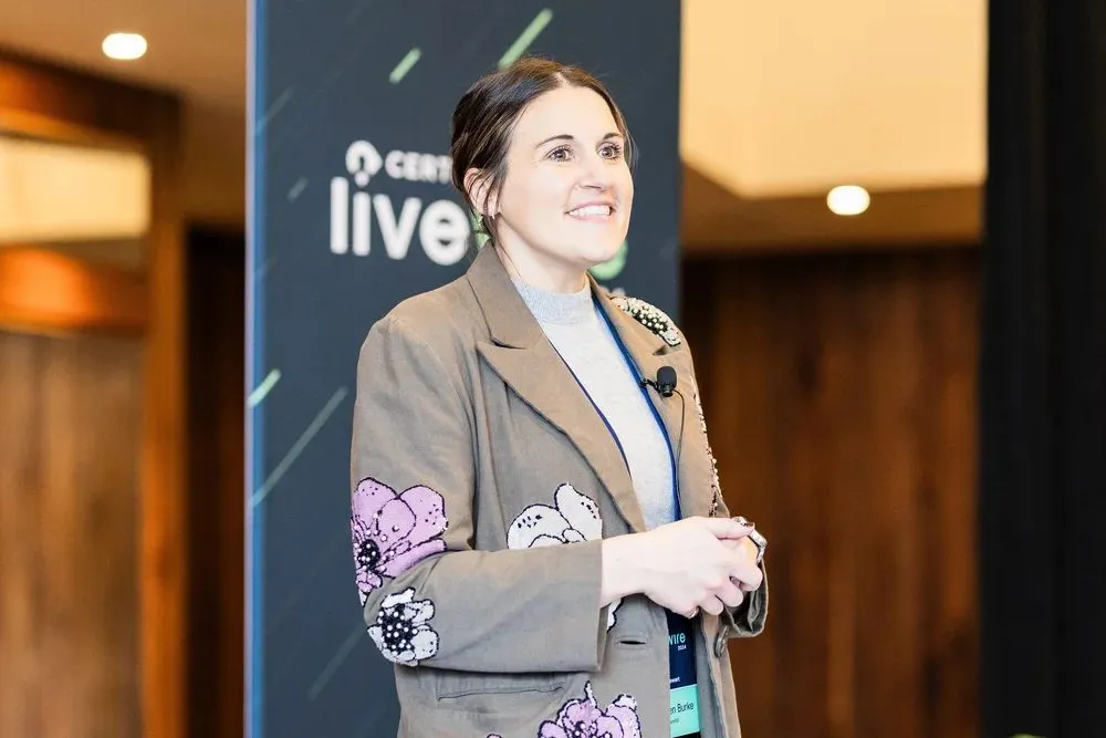 Speaker smiling in front of a branded banner at a customer summit