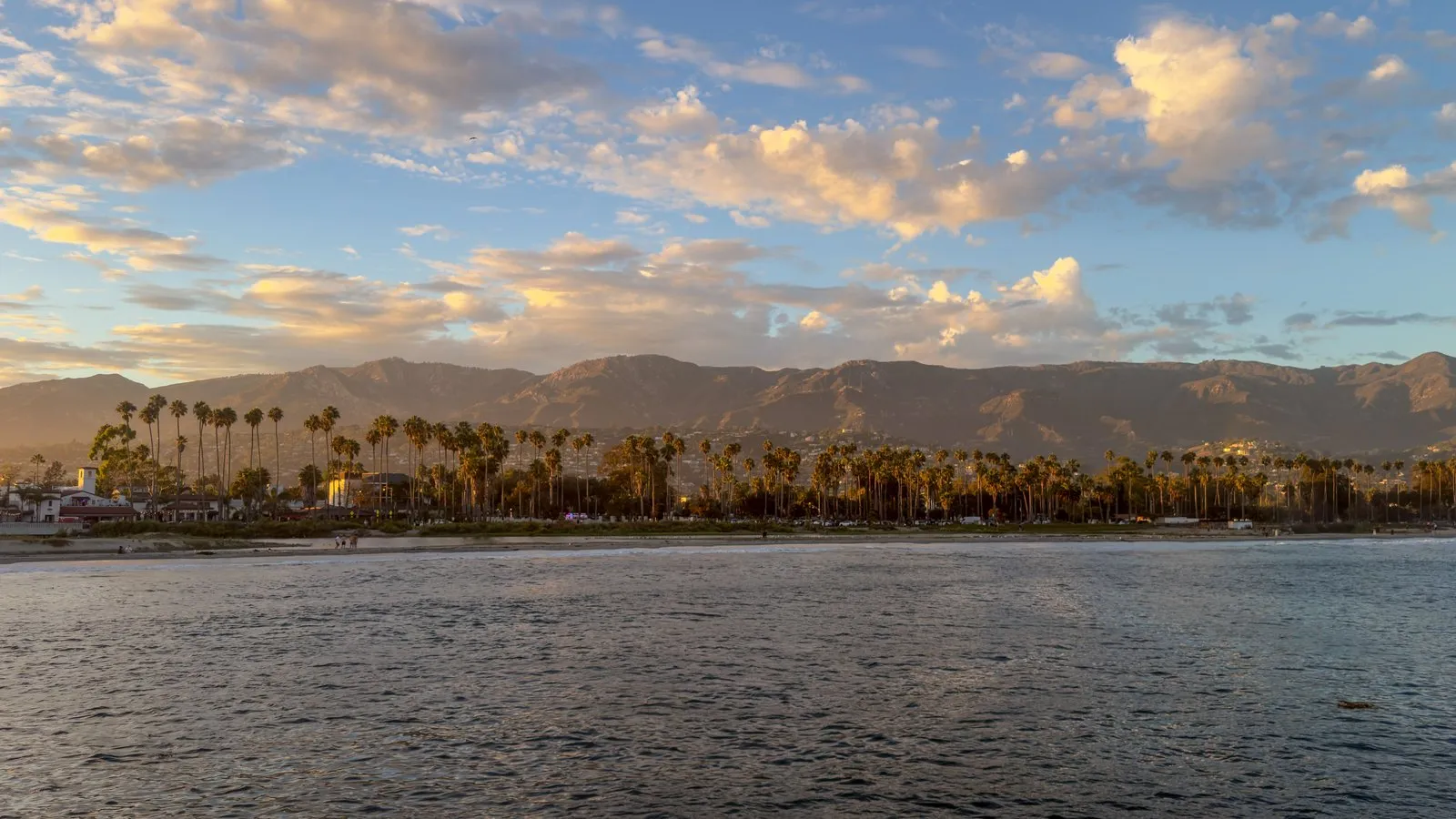 Palm-lined Santa Barbara waterfront at sunset, foothills behind.