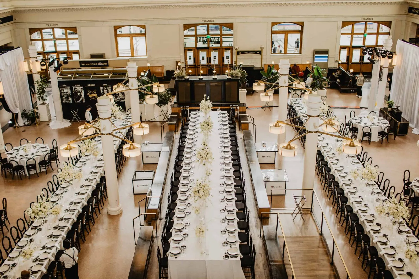 Long dinner tables with white florals in the Great Hall of Denver Union Station for TransMedics