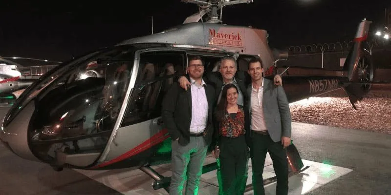 Guests posing in front of a helicopter at night