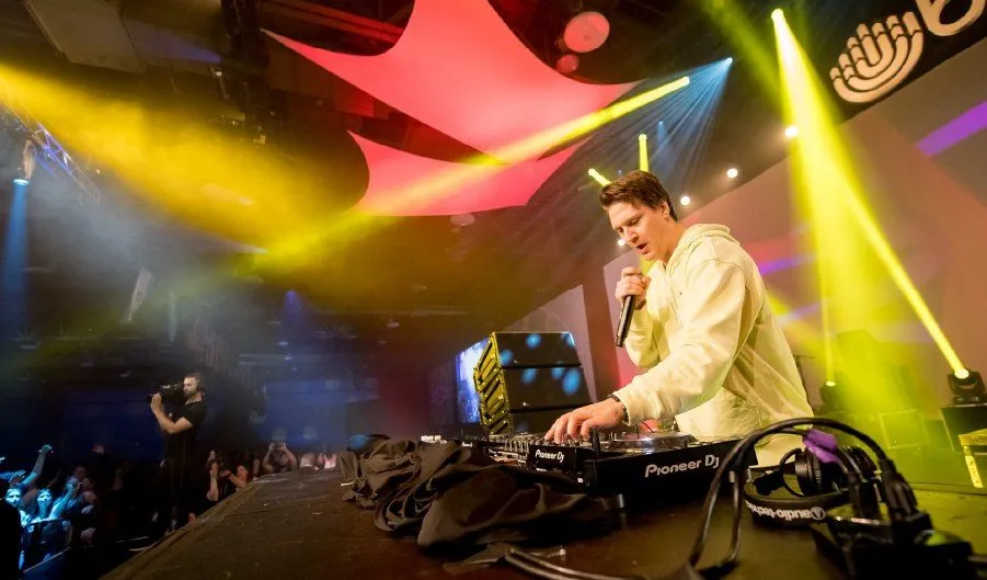DJ performing under bright stage lights at an evening event