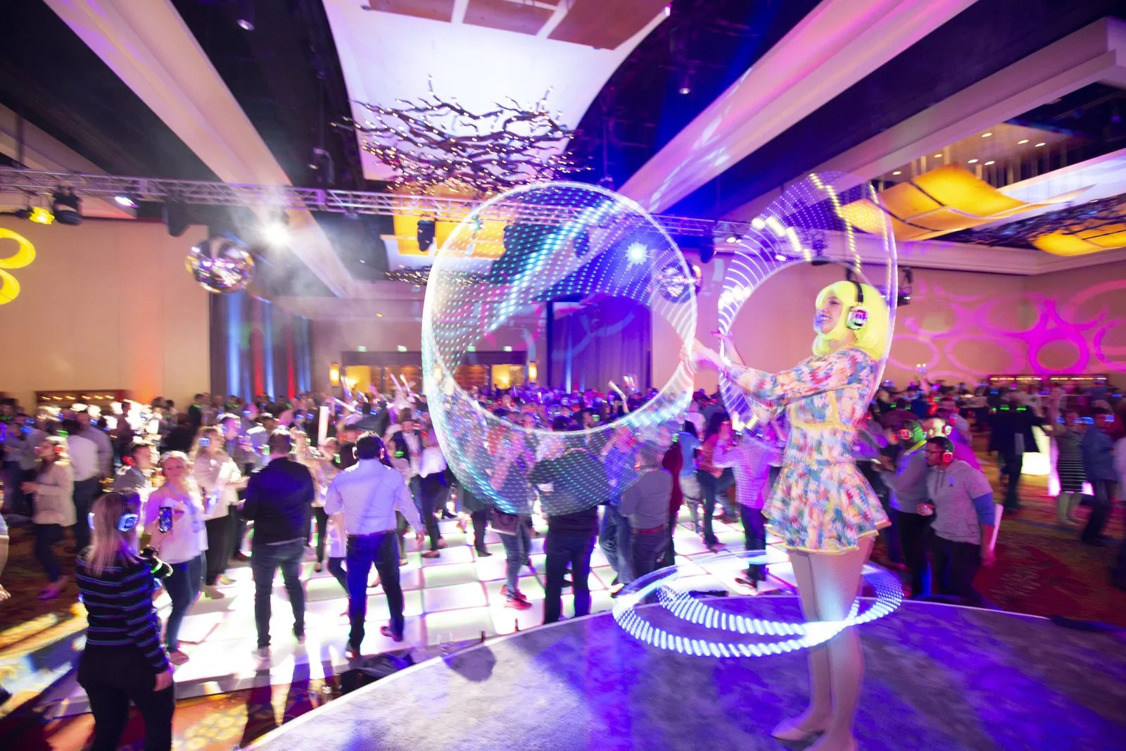 Celebration party with guests on a dance floor and a performer in a glowing bubble