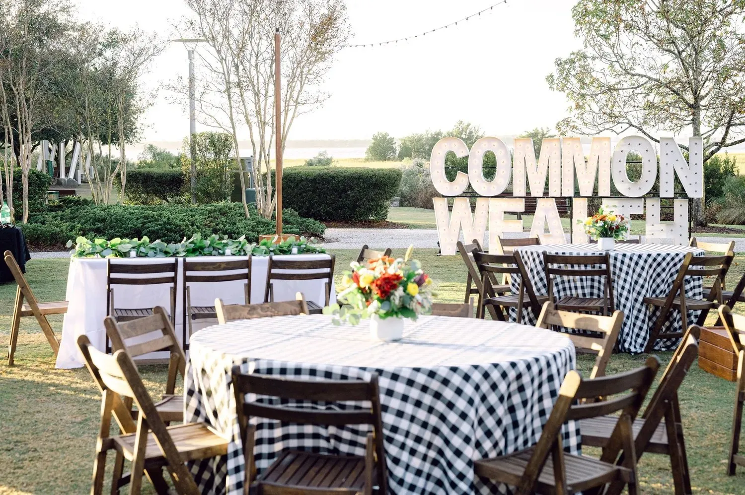 Outdoor dinner with gingham linens and a "Commonwealth" marquee sign