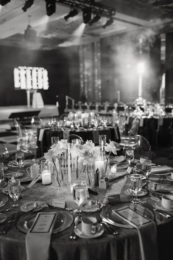 Black and white view of round tables and stage lighting set for a corporate event