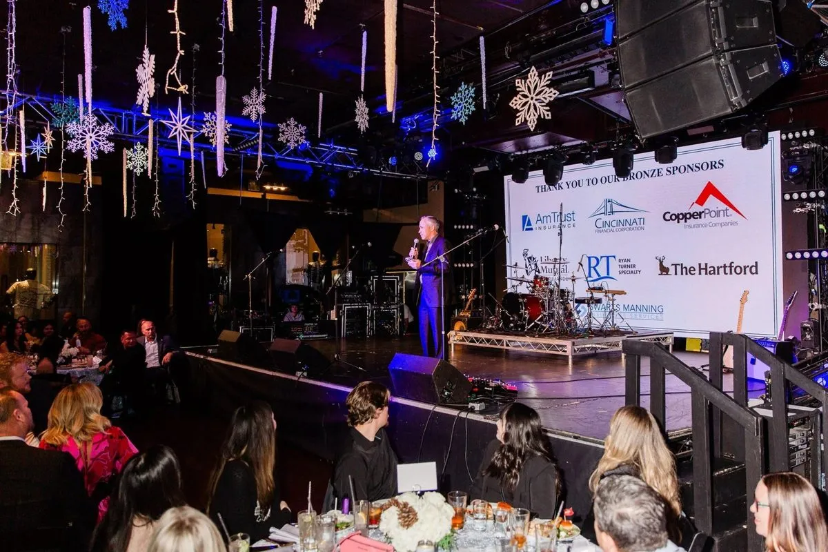 Evening event with a speaker on stage and a screen showing sponsor logos