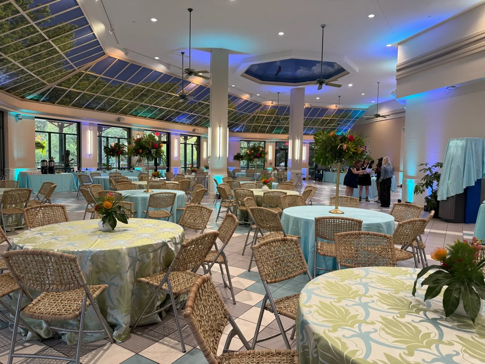 Atrium event space set with round tables, centerpieces and blue accent lighting
