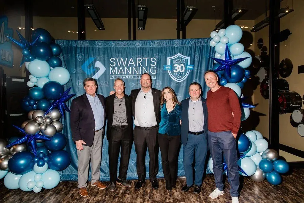 Six people posing in front of a Swarts Manning backdrop with balloon garlands