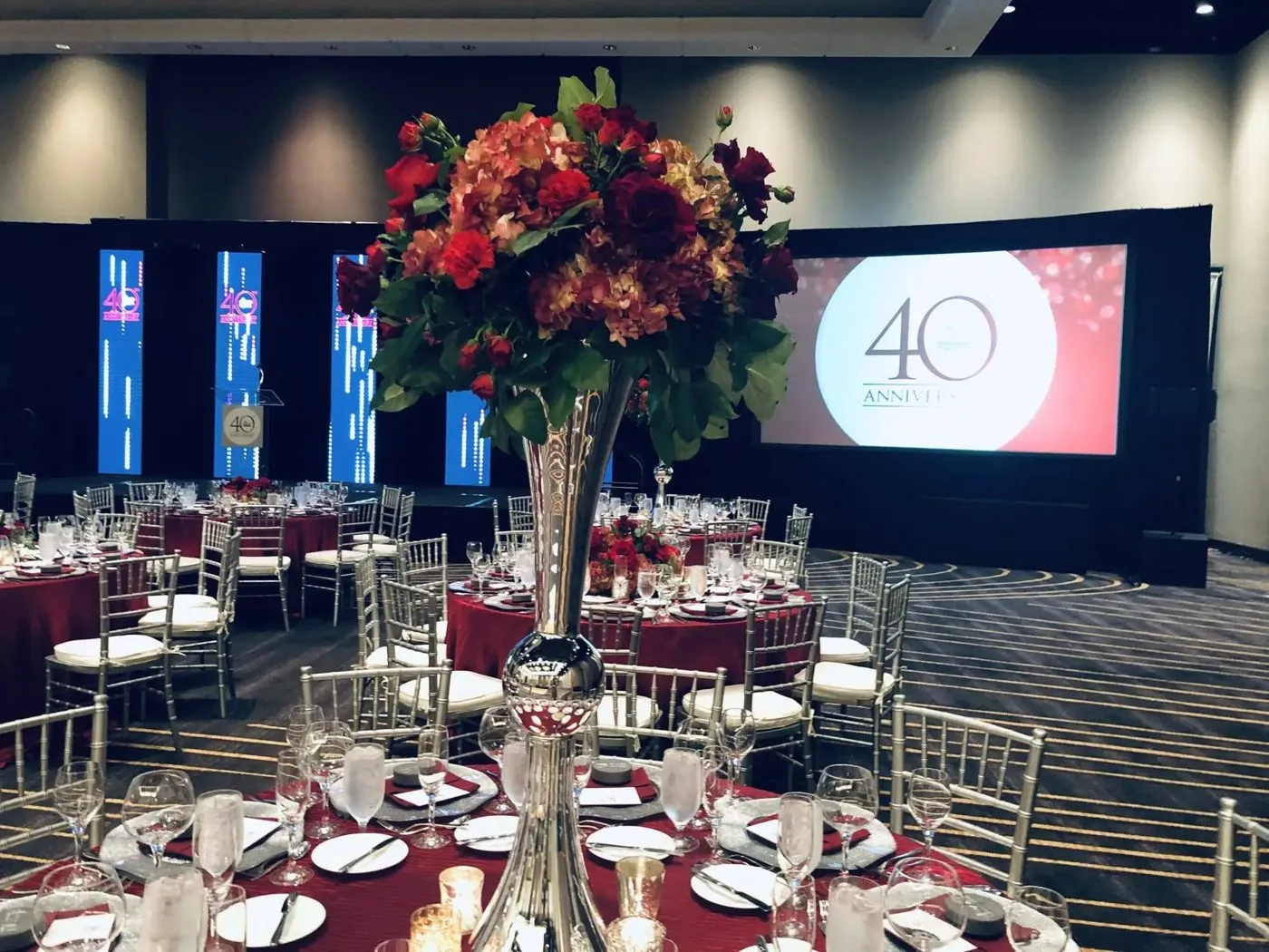 Company anniversary dinner room with centerpieces and a stage screen