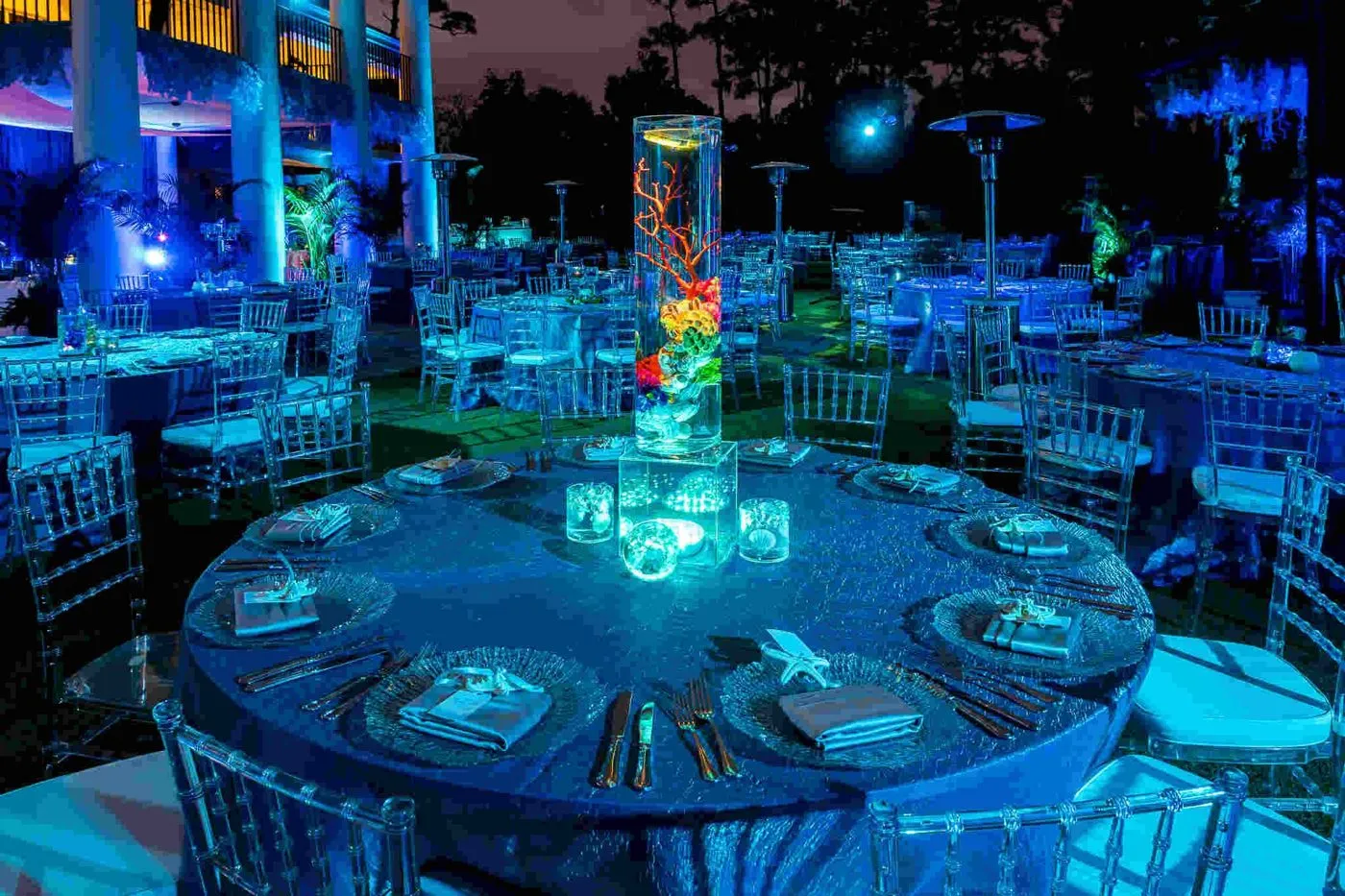 Blue lit round tables set outdoors for an evening corporate dinner