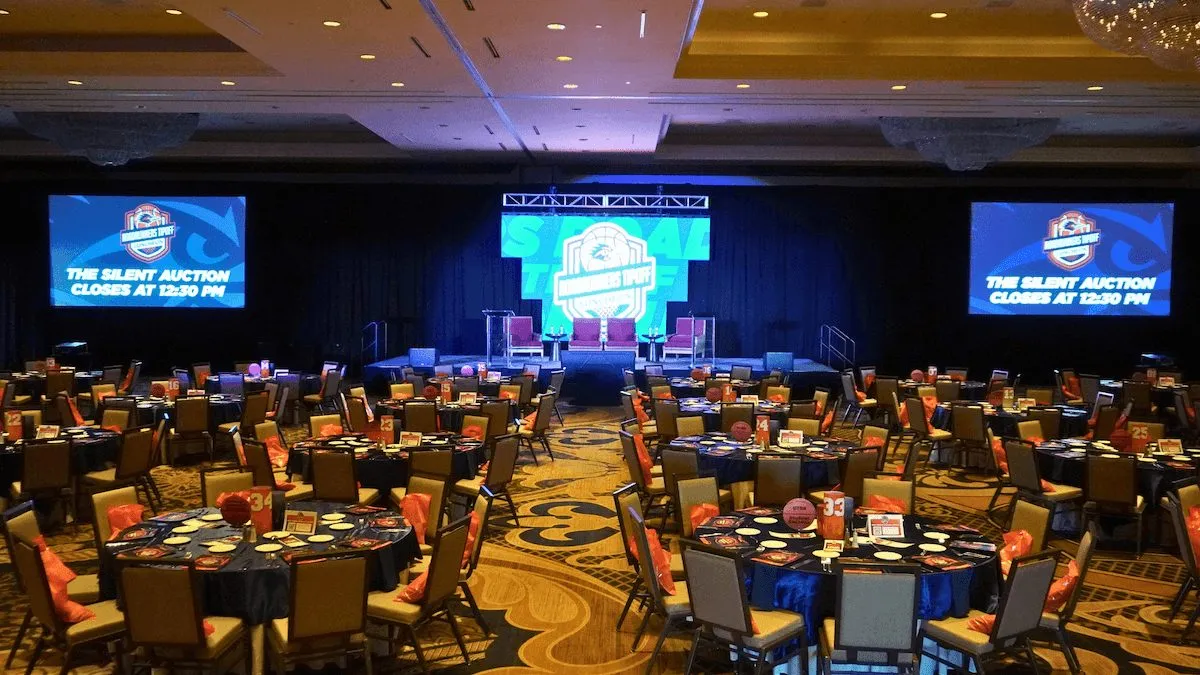 Ballroom with round tables and large screens set for a business event