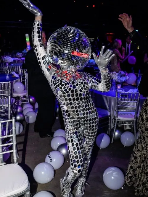 Performer in a mirrored disco ball costume among balloons at a company party