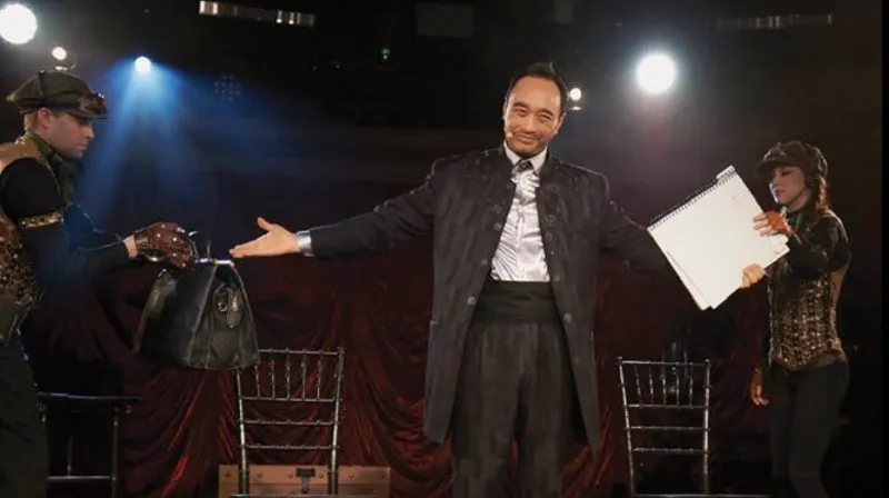 Performer on a lit stage in front of a seated audience