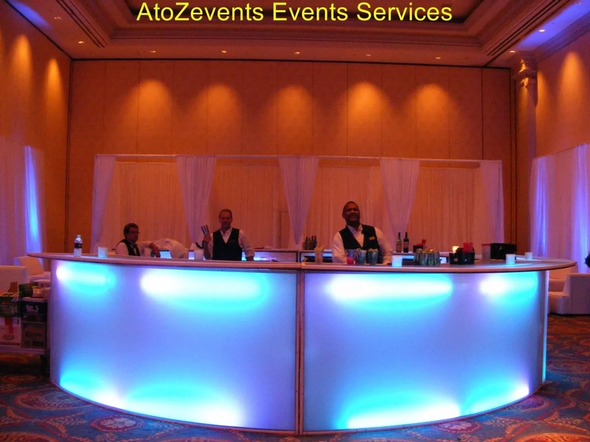Illuminated curved bar in a ballroom with orange draping
