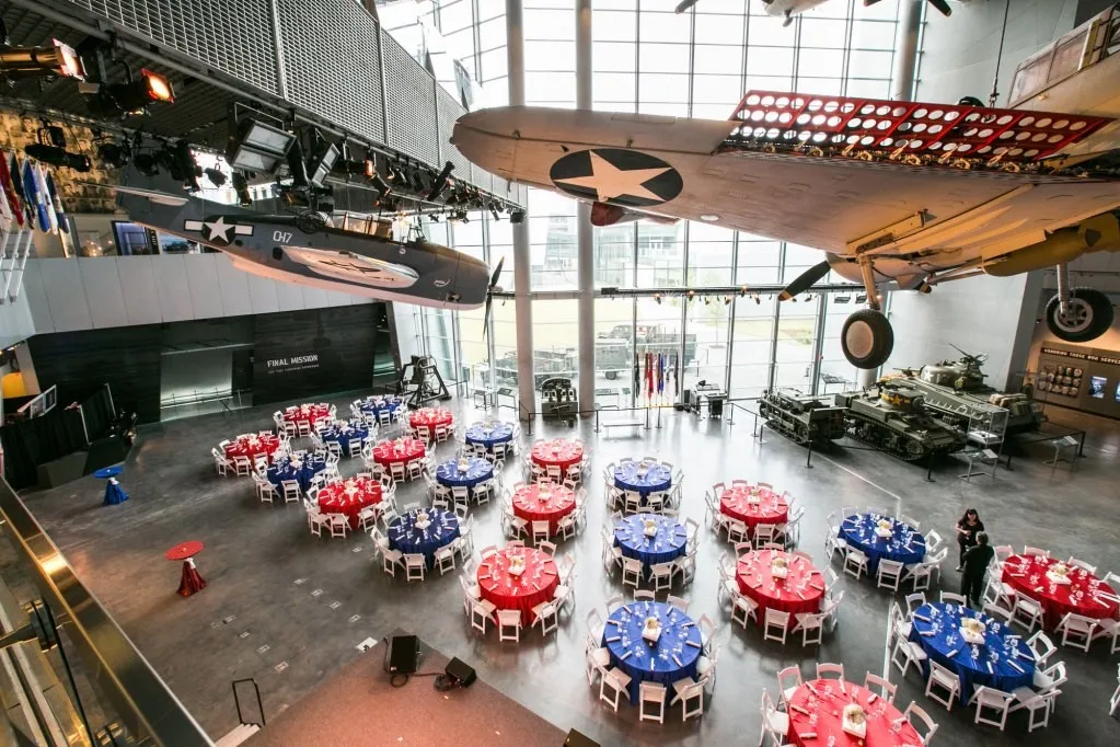 Large banquet set with colorful tables under a high ceiling