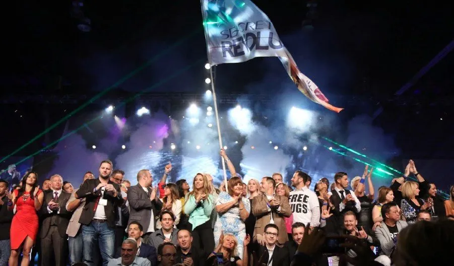 Crowd cheering in front of a lit stage at a company event