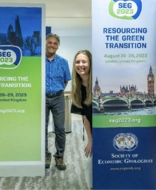 Two conference attendees beside event banners at a meeting