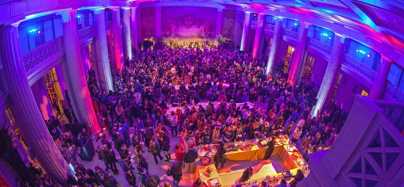 Audience seated beneath a domed ceiling lit in purple