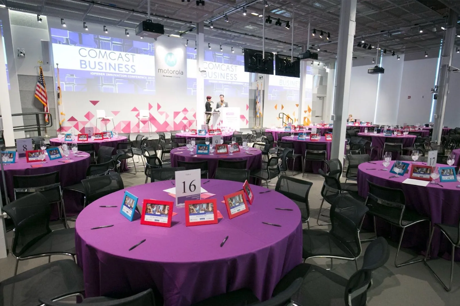 Ballroom set with round tables in purple linens and a stage