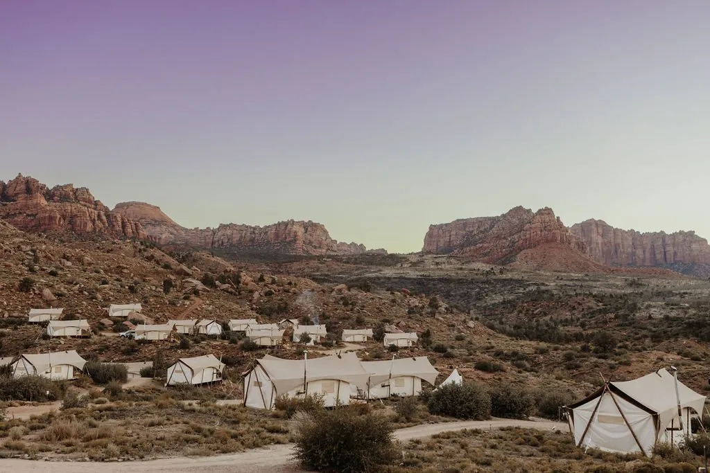 Tents at a company retreat camp below red-rock cliffs near Zion