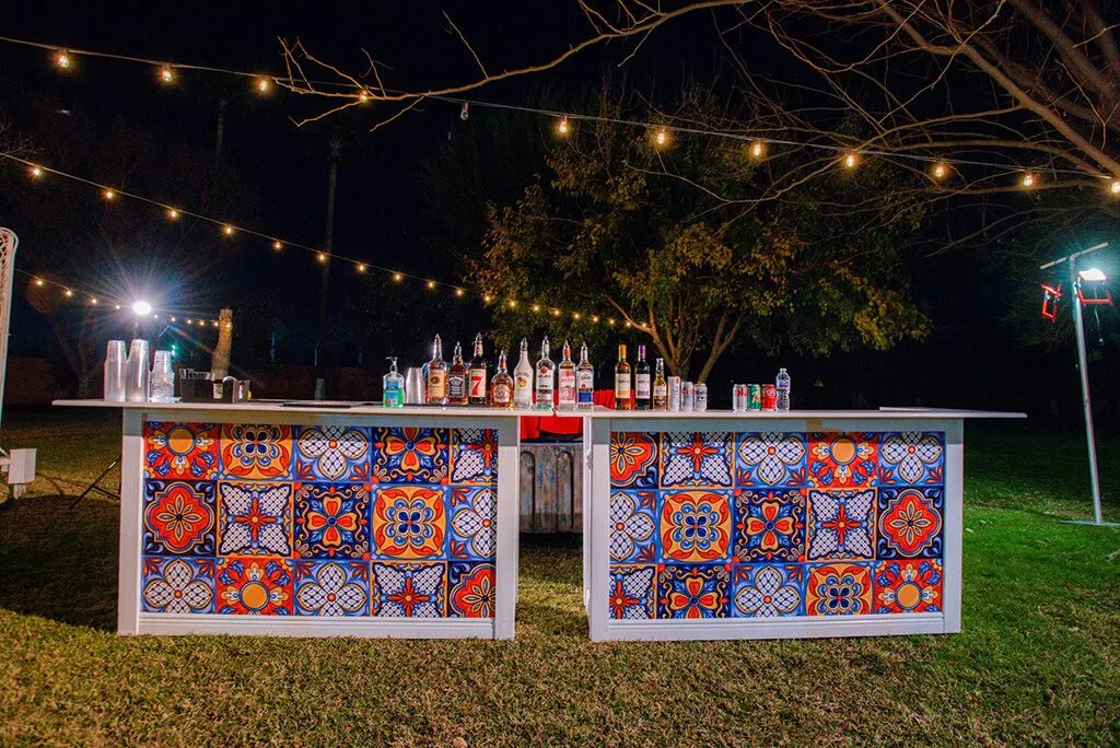 Outdoor bar with colorful tile front under string lights at night