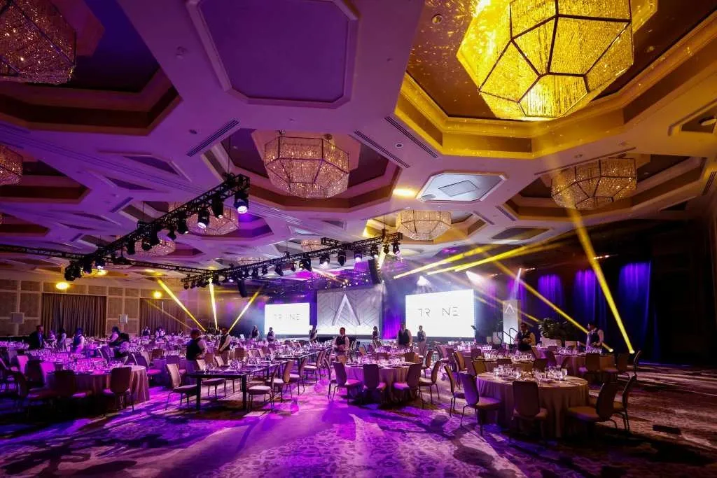 Ballroom set with round tables and purple stage lighting for a corporate general session