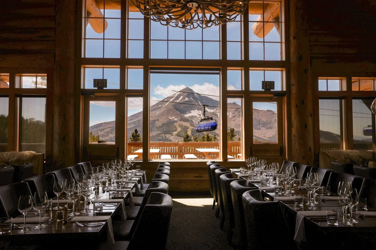 Long dinner tables with Lone Peak in the windows at Everett's 8800 in Big Sky