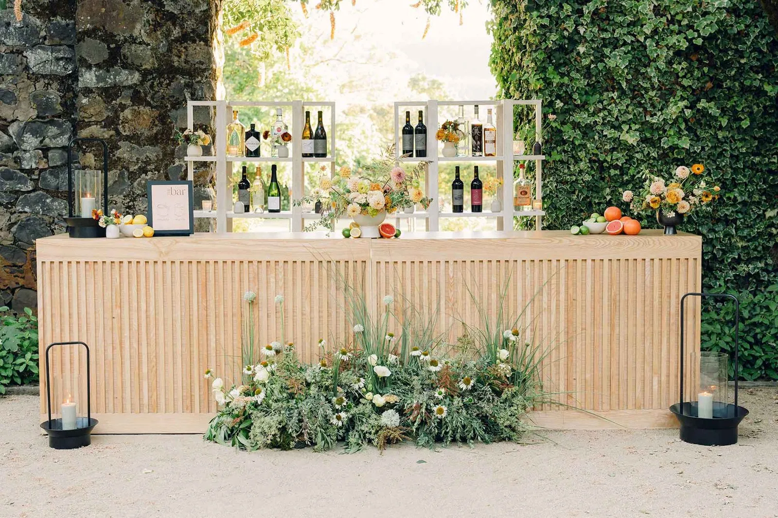 Wooden outdoor bar with wine display and floral arrangements
