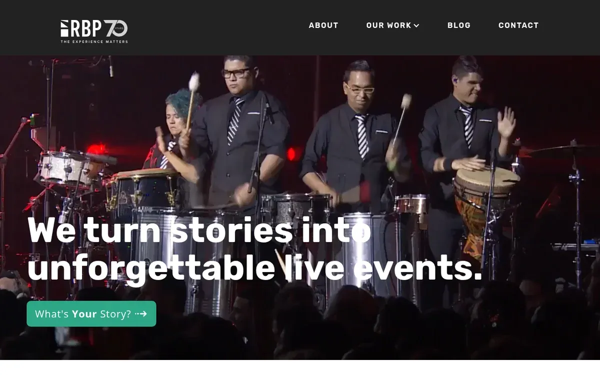 Ray Bloch Productions homepage hero with the RBP wordmark, the headline We turn stories into unforgettable live events, a What's Your Story? button, and a percussion ensemble in black shirts and ties playing drums on a dark stage