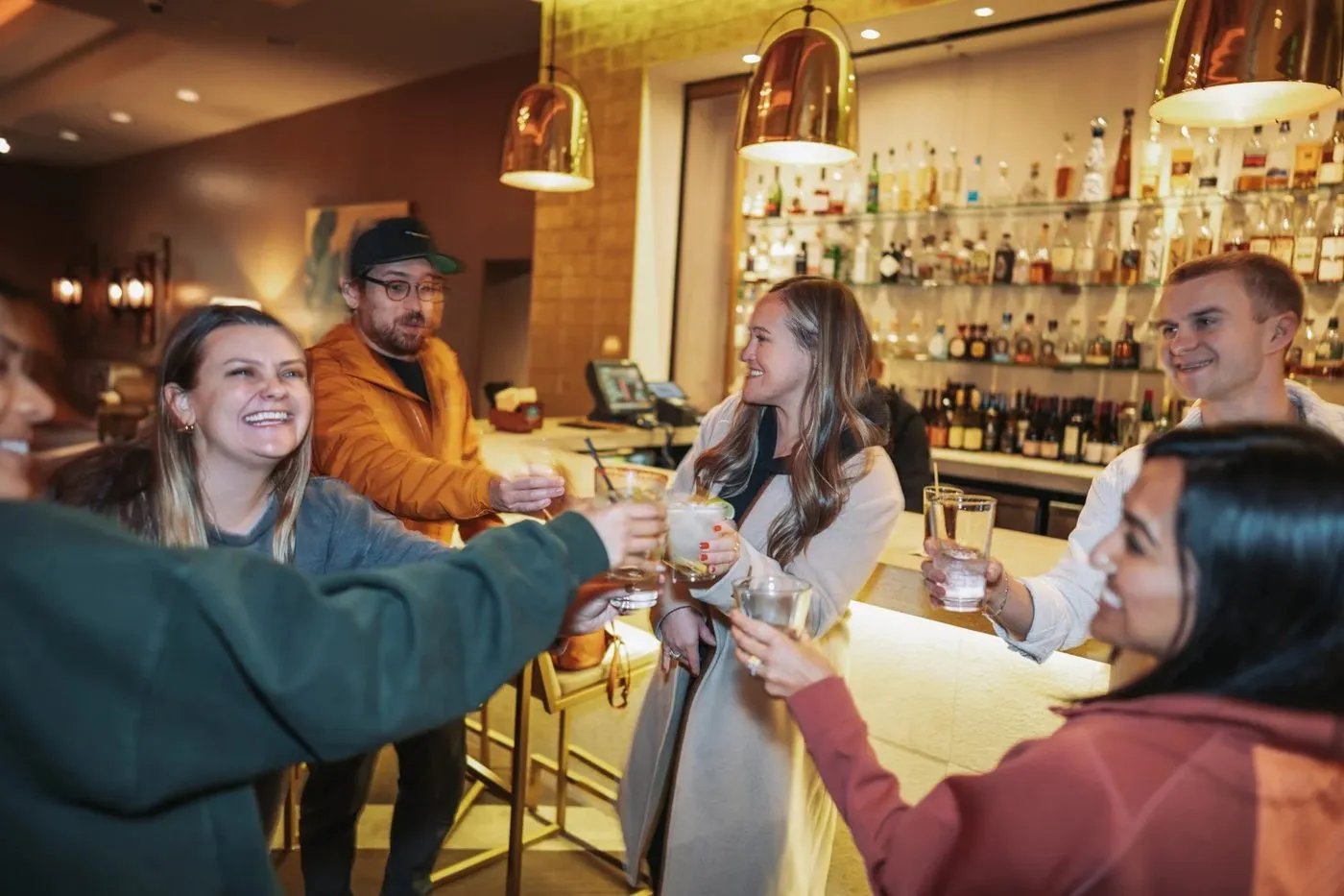 Guests raising glasses together at a bar during a team offsite reception