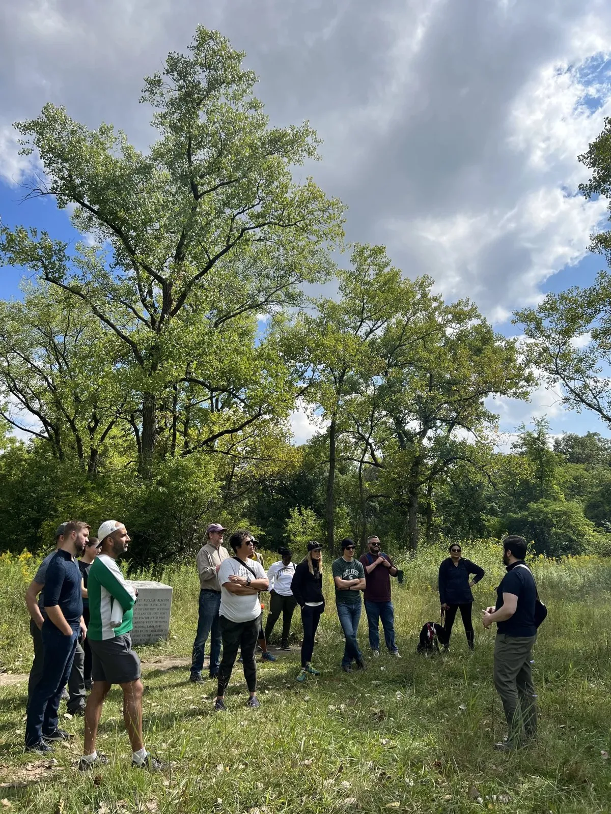 Group standing in a circle in a wooded meadow during an outdoor retreat
