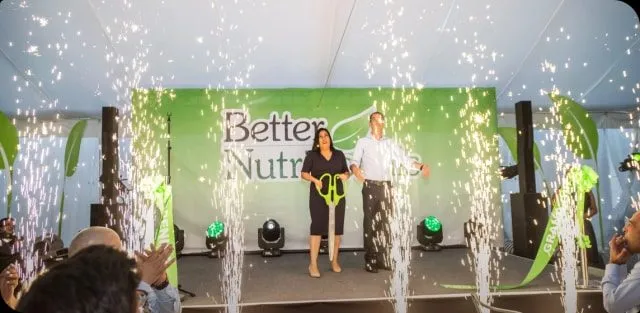 Two speakers on a stage with sparkler effects and a green backdrop