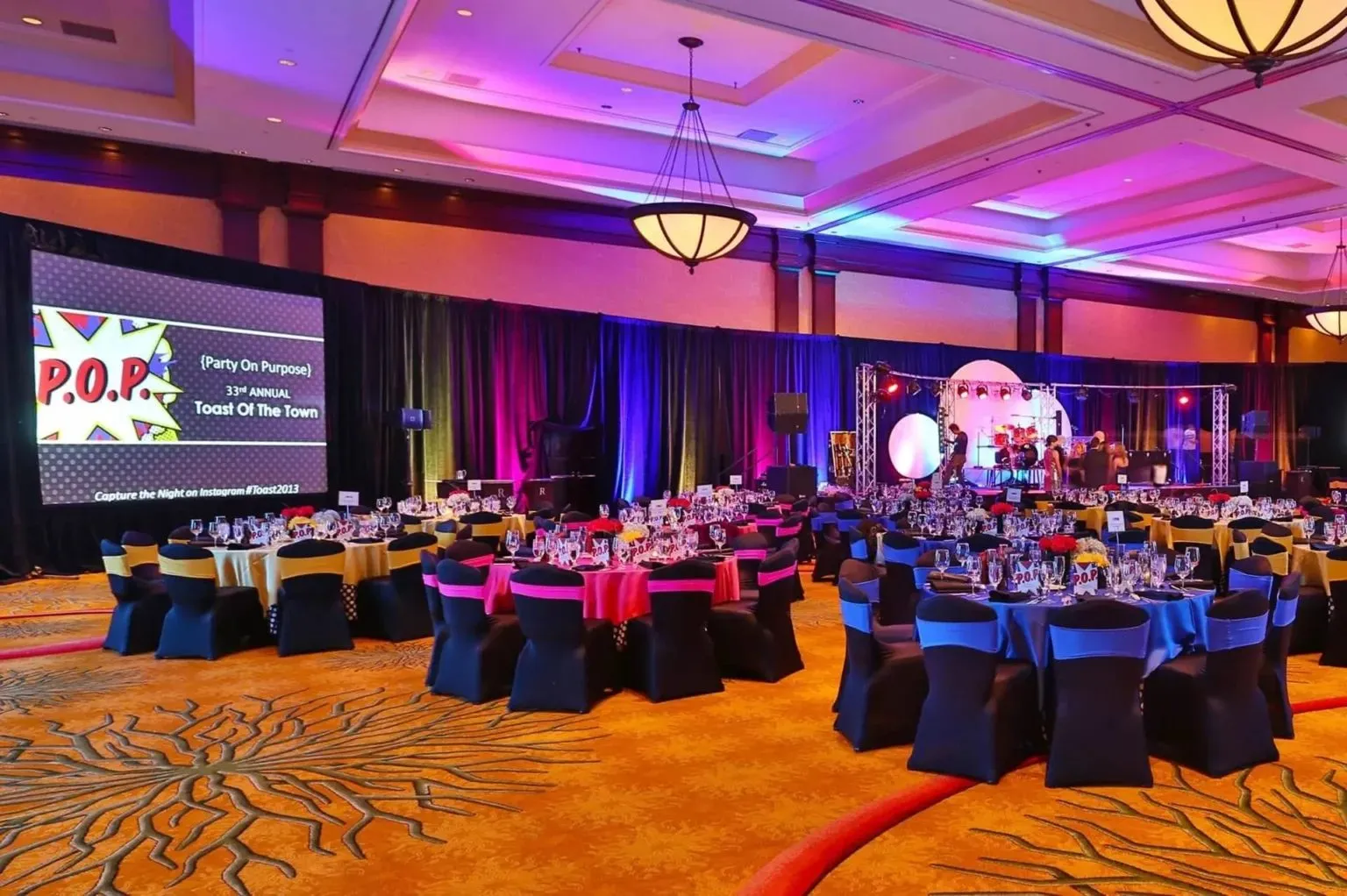 Ballroom with round tables and purple lighting set for a corporate event