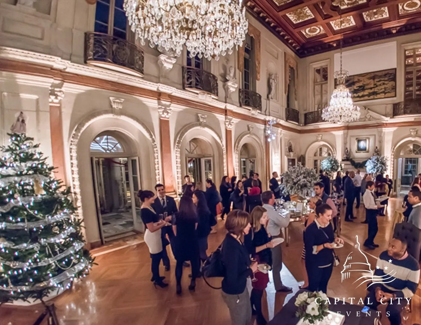 Reception in a grand ballroom with a decorated tree and guests mingling