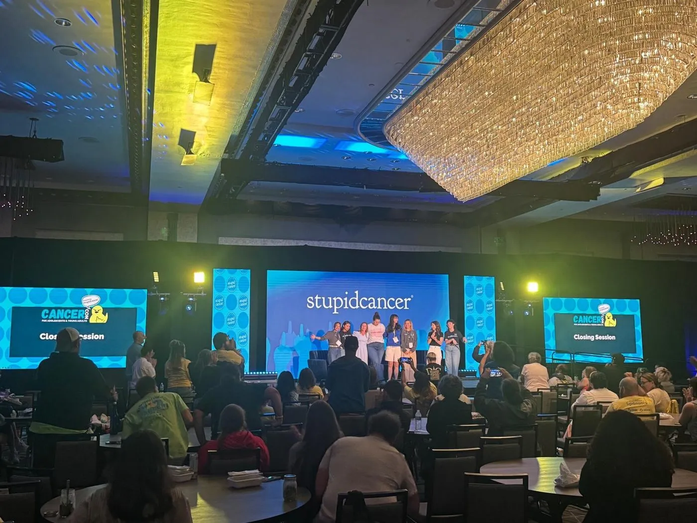 Hotel ballroom conference stage with LED screens and a seated audience
